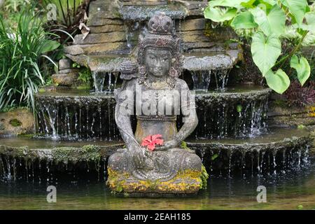 Indonésie Bali - Ubud statue en pierre balinaise faite à la main avec du rouge Fleur d'hibiscus Banque D'Images