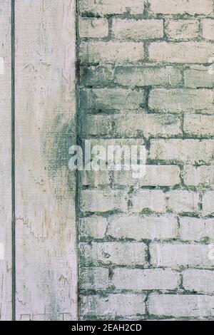 Image verticale en gros plan d'un mur de briques grungy blanchi à la chaux dans une peinture vert pâle, avec une bordure en bois blanc à gauche, une image utile pour l'espace de copie Banque D'Images