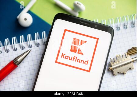 Dans cette illustration, un logo Kaufland apparaît sur un smartphone avec un stylo, une clé, un livre et des casques en arrière-plan. Banque D'Images