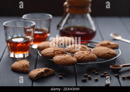 Gadget de brassage du café. Café goutte-à-goutte fraîchement préparé et verres servis avec des biscuits aux flocons d'avoine et des grains de café sur fond noir horizontal Banque D'Images