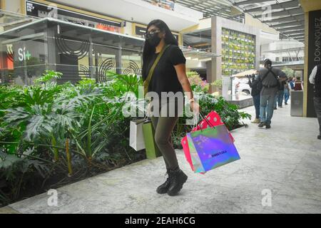 Mexique, Mexique. 09e février 2021. Une dame portant un masque facial porte des sacs de shopping au Antara Fashion Hall.dans le cadre du programme « Activer sans risque », les centres commerciaux et les grands magasins ont été ouverts ce mardi avec un programme allant jusqu'à 24 heures pour soutenir l'économie. Selon le ministère du développement économique (Sedeco), on estime que plus de 66 000 personnes reviendront à leur emploi. Crédit : SOPA Images Limited/Alamy Live News Banque D'Images