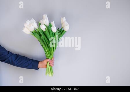Homme tenant un bouquet de magnifiques tulipes blanches de printemps. Fleurs à offrir. Placer pour le texte. Banque D'Images