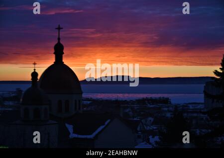 Un beau lever de soleil illumine une église en dôme et le lac supérieur, avec le parc provincial « géant rampant » en arrière-plan. Banque D'Images