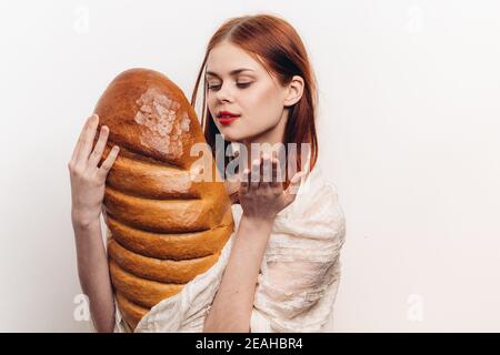 femme tenant un grand pain et un maquillage brillant dans elle Modèle de vêtement léger pour les mains Banque D'Images