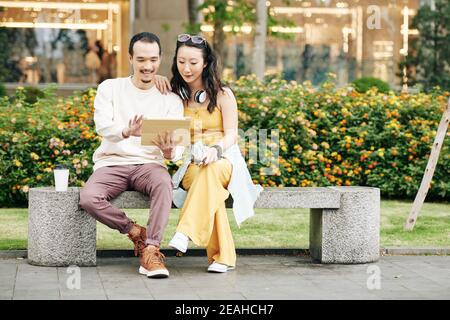 Couple avec une tablette assise sur un banc Banque D'Images