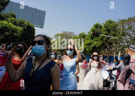 Yangon, Myanmar. 10 février 2021. Les manifestants portant des robes de mariée marchent dans la rue pendant la manifestation. Des milliers de personnes sont descendues dans les rues de Yangon le cinquième jour de protestation contre le coup d'État militaire et ont demandé la libération d'Aung San Suu Kyi. L'armée du Myanmar a arrêté le conseiller d'État du Myanmar Aung San Suu Kyi le 01 février 2021 et a déclaré l'état d'urgence tout en prenant le pouvoir dans le pays pendant un an après avoir perdu les élections contre la Ligue nationale pour la démocratie (NLD). Crédit : SOPA Images Limited/Alamy Live News Banque D'Images