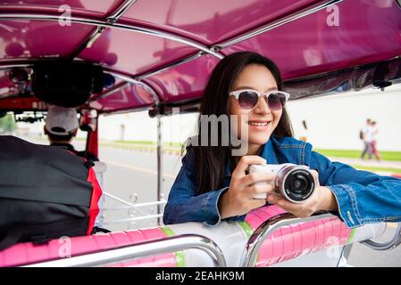 Souriante femme asiatique touriste tenant un appareil photo sur tuk tuk Taxi à Bangkok Thaïlande pendant les vacances d'été en solo Banque D'Images