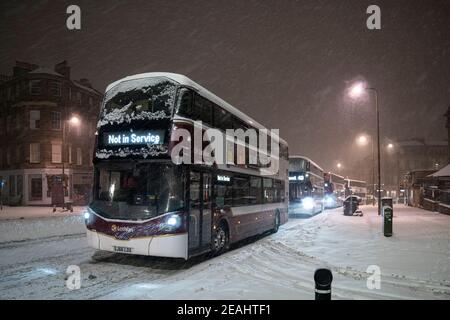 Édimbourg, Écosse, Royaume-Uni. 10 févr. 2021. Le gros gel se poursuit au Royaume-Uni avec de la neige abondante de nuit et du matin, ce qui immobilise la circulation sur de nombreuses routes du centre-ville. Pic ; les bus Lothian luttent sur Leith Walk à 6h du matin. Iain Masterton/Alamy Live News Banque D'Images