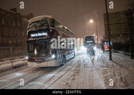 Édimbourg, Écosse, Royaume-Uni. 10 févr. 2021. Le gros gel se poursuit au Royaume-Uni avec de la neige abondante de nuit et du matin, ce qui immobilise la circulation sur de nombreuses routes du centre-ville. Pic ; les bus Lothian luttent sur Leith Walk à 6h du matin. Iain Masterton/Alamy Live News Banque D'Images