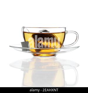 Thé dans une tasse en verre avec soucoupe sur blanc avec reflet Banque D'Images