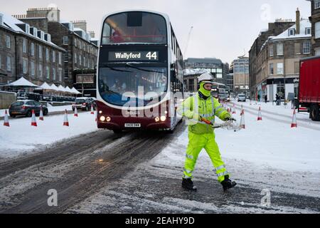 Édimbourg, Écosse, Royaume-Uni. 10 févr. 2021. Le gros gel se poursuit au Royaume-Uni avec de la neige abondante de nuit et du matin, ce qui immobilise la circulation sur de nombreuses routes du centre-ville. Pic ; les ouvriers répandaient le sel à la main au rond-point sur Lothian Road et Leith Walk. . Iain Masterton/Alamy Live News Banque D'Images