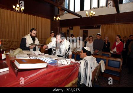 Une cérémonie de Brit Mila a lieu sur la bimah de la synagogue dans le Solihull, West Midlands, comme le Mohel donne les bénédictions traditionnelles comme il commence la circoncision surveillée par le rabbin et les membres de la famille. Banque D'Images