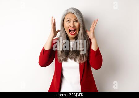 Femme d'affaires asiatique criant et regardant outragé, se sentant affligé et criant, debout contre fond blanc Banque D'Images