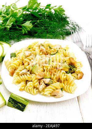 Fusilli avec poulet et courgettes dans une assiette sur panneau lumineux Banque D'Images