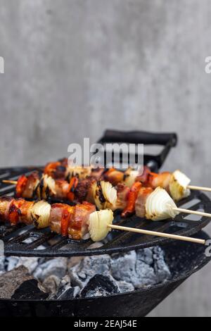 brochette d'oignon rouge et de porc fumé sur un barbecue de jardin Banque D'Images