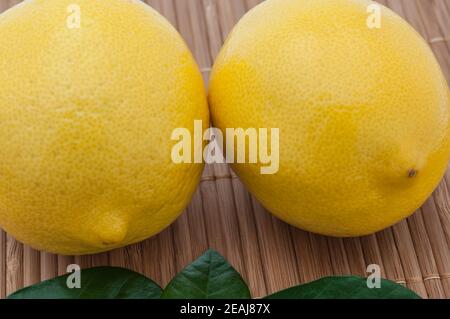 Gros citrons jaune et vert feuilles close-up sur le tapis de bambou. Banque D'Images