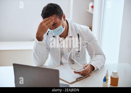 Thérapeute fatigué avec stéthoscope sur les épaules après une longue journée dure avec des patients dans un centre médical Banque D'Images