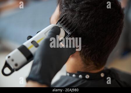 Homme aux cheveux sombres et lumineux passant du temps dans un salon de beauté lors de la réception d'un nouveau coiffage Banque D'Images