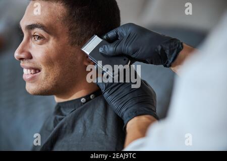 Main de coiffeur dans les gants de médecine faisant un nouveau style pour le client dans le salon de beauté Banque D'Images