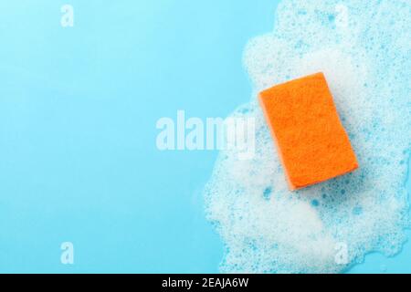 Éponge orange et mousse sur fond bleu Banque D'Images