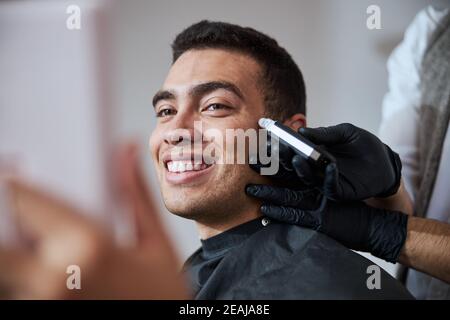 Beau homme plein de confiance en soi avec un beau sourire se coiffant salon de beauté Banque D'Images