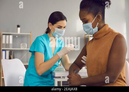 Femme médecin faisant la vaccination contre le covid-19 pour la femme noire Banque D'Images