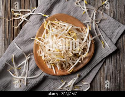 Le haricot s'élance dans une assiette en bois contre un ancien arrière-plan en bois Banque D'Images