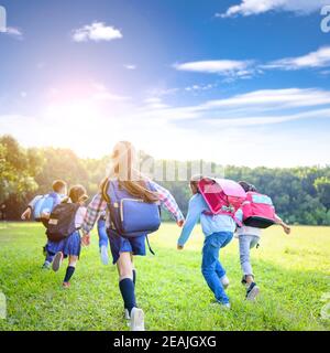 vue arrière des enfants de l'école primaire qui s'amusent sur l'herbe Banque D'Images