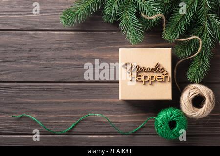 Boîte cadeau de Noël avec lettres en bois miracles se produisent. Idées d'emballage de cadeaux. Design naturel. Banque D'Images