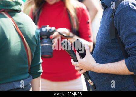 Journaliste à l'événement médiatique tenant un microphone, une femme photographe floue en arrière-plan Banque D'Images