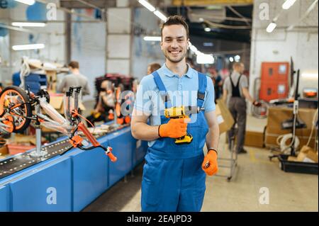 Usine de vélos, l'employé tient un tournevis électrique Banque D'Images