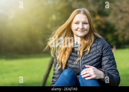 Portrait d'une jeune femme aux cheveux rouges posant à l'extérieur Banque D'Images