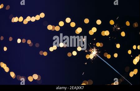 Sparkler brûlant avec fond de bokeh festif pour le nouvel an et le concept de Noël, espace pour le texte Banque D'Images