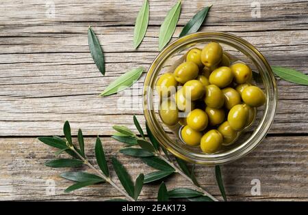 Branches d'olive aux olives salées placées sur un fond de anciennes planches en bois Banque D'Images