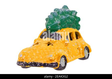 Décorations de Noël arrière-plan. Gros plan d'un jouet de voiture jaune recouvert de neige avec sapin vert sur le toit isolé sur un fond blanc. Élément Saisonal design pour cartes ou autocollants. Macro. Banque D'Images