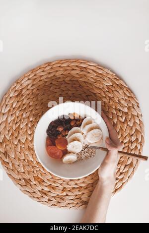 Glucides petit déjeuner sain flocons d'avoine avec fruits secs sur une assiette blanche. Vue de dessus Banque D'Images