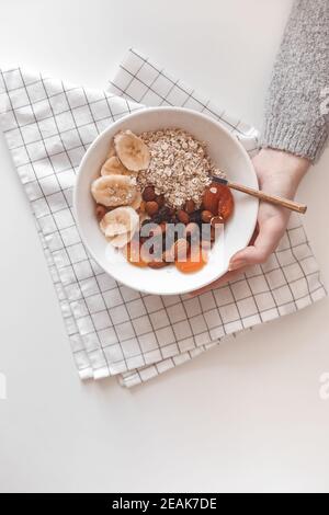 Un petit déjeuner sain aux glucides. Flocons d'avoine avec fruits séchés sur une assiette blanche. Vue de dessus Banque D'Images