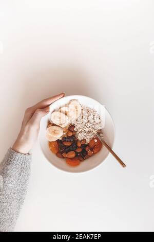 Un petit déjeuner sain aux glucides. Flocons d'avoine avec fruits séchés sur une assiette blanche. Vue de dessus Banque D'Images