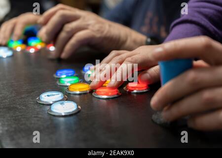 Gros plan de deux mains de personnes jouant arcade jeux vidéo vintage.manette de jeu avec manette et de nombreux boutons colorés .amis ludiques, amusement et passe-temps Banque D'Images