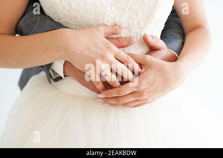 Jeune couple marié tenant les mains avec des anneaux sur fond blanc, cérémonie de mariage jour Banque D'Images