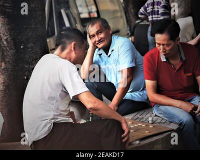 HONG KONG, CHINE - 09 févr. 2021 : trois hommes jouant aux Dames dans la rue Banque D'Images