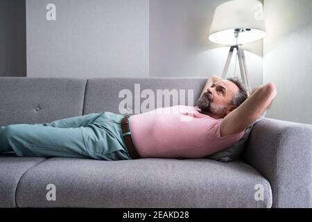 Homme âgé se détendant sur un canapé Banque D'Images