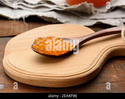 saumon rose caviar rouge dans une cuillère marron en bois la table Banque D'Images