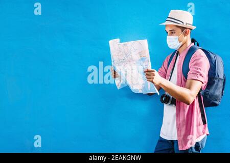 homme adulte avec un sac à dos portant un masque tenant et regarder une carte.f Banque D'Images