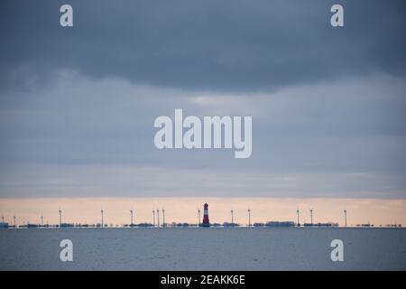 Wilhelmshaven, Allemagne. 10 février 2021. Nuages gris au-dessus des éoliennes et un phare à la baie de Jade. Credit: Jonas Walzberg/dpa/Alay Live News Banque D'Images