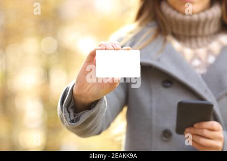 Une femme tient le téléphone et montre sa carte de crédit à l'automne Banque D'Images