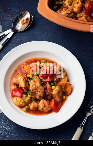 Ragoût de poulet avec pommes de terre, paprika, pois et maïs sur une assiette blanche. Ragoût de poulet cuit lentement dans un bol en céramique. Vue de dessus. Banque D'Images