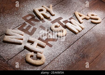 L'inscription merry Christmas-cookies sous forme de lettres faites de pâte de gingembre. Biscuit au gingembre. Travail fait à la main. Imprimer sur un arrière-plan en bois. Le concept de la célébration. Noël ou nouvel an. Banque D'Images