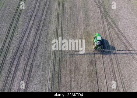 Tracteur avec système de pulvérisation de pesticides sur charnières. Fertilisation avec un tracteur, sous forme d'aérosol, sur le champ de blé d'hiver. Banque D'Images