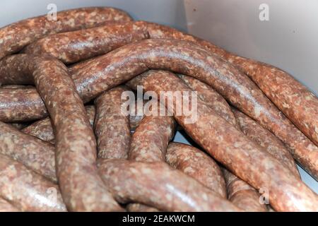 Gros plan de saucisses crues dans des boyaux reposant dans un bain Banque D'Images